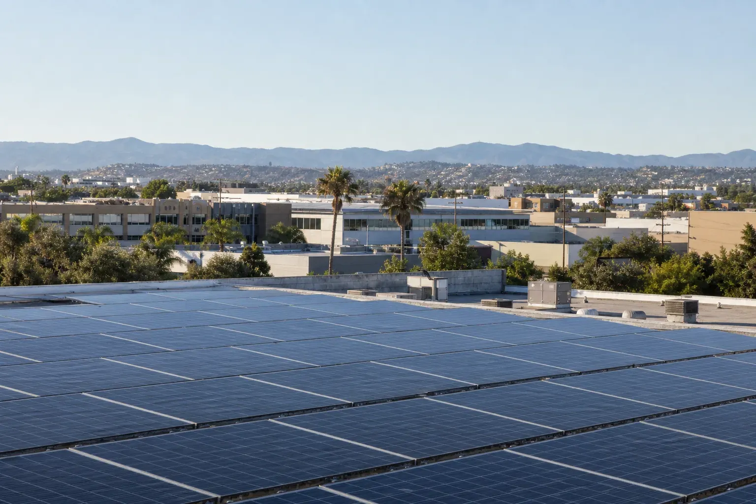 Broad commercial rooftop solar array overlooking a mixed Anaheim business district and distant hills.