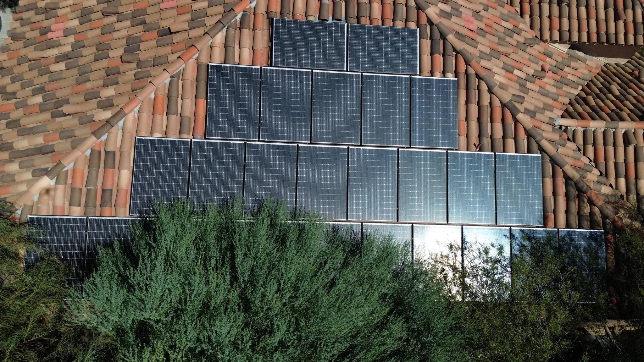 Overhead drone view of a stepped solar array on a multicolor clay tile roof in the Coachella Valley