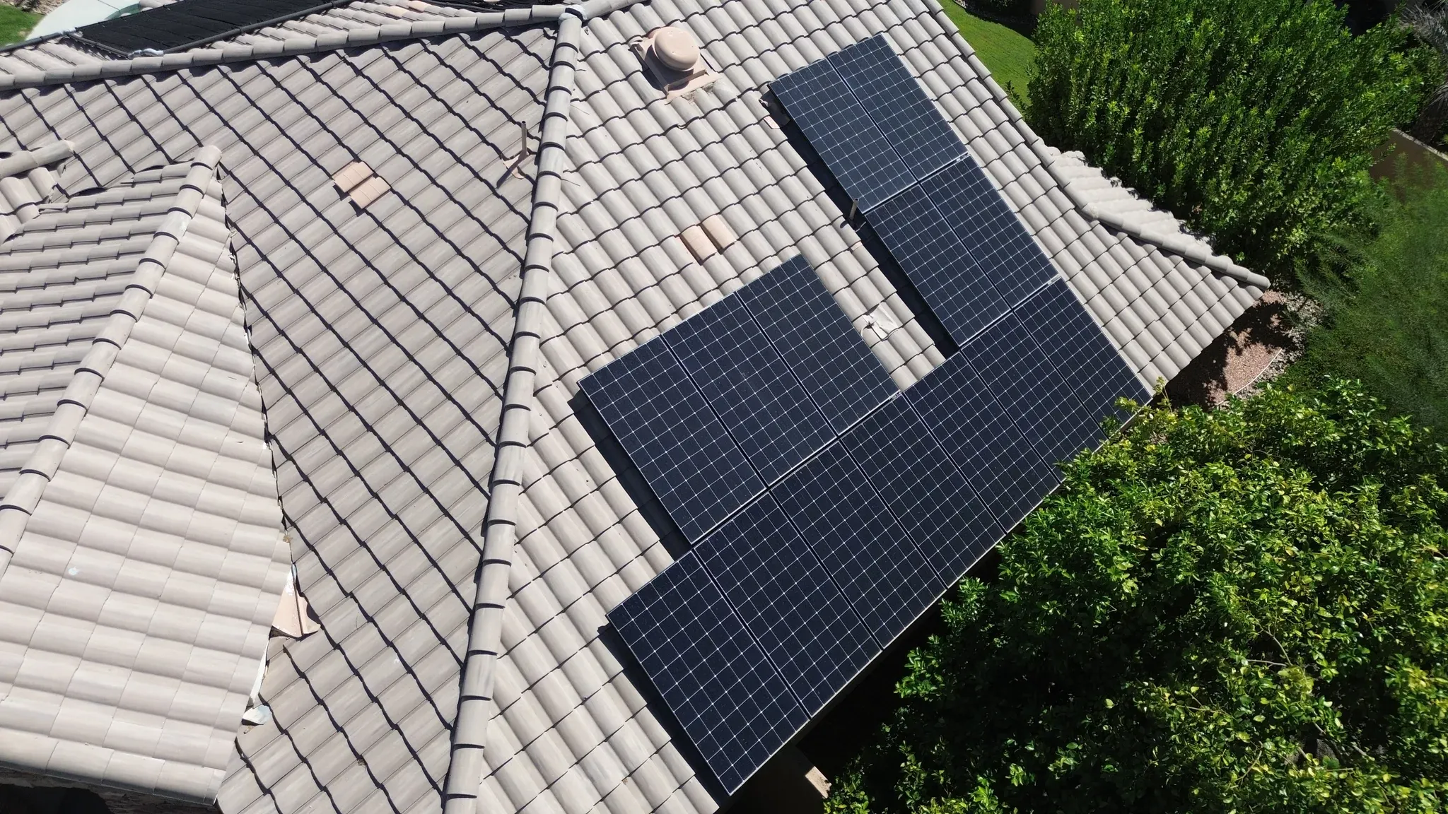 Drone view of an L-shaped solar array on a tan concrete tile roof in the Coachella Valley, dulled by dust before a DronePower1 cleaning