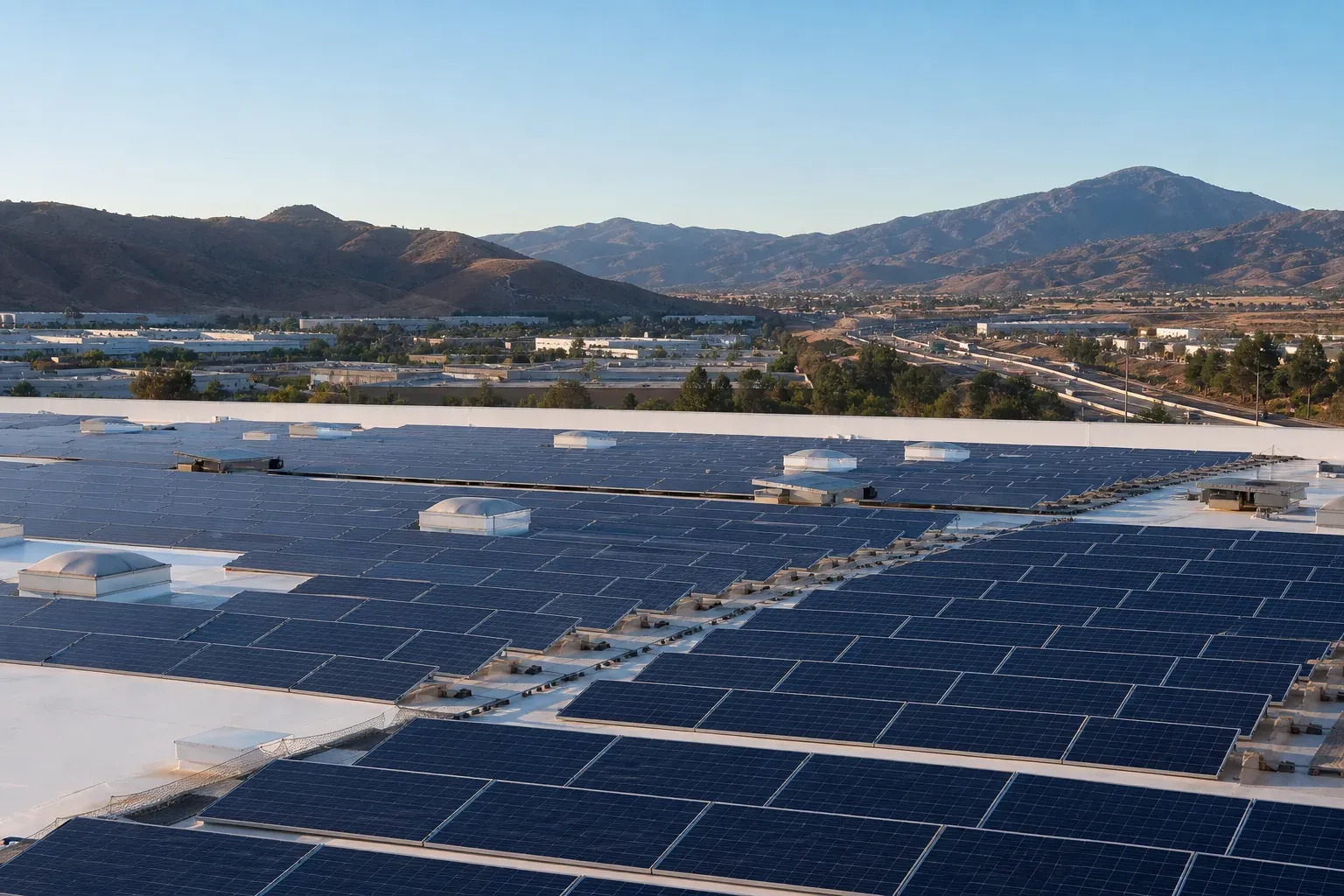 Large commercial rooftop solar array in Corona with the I-15 corridor and canyon foothills beyond.