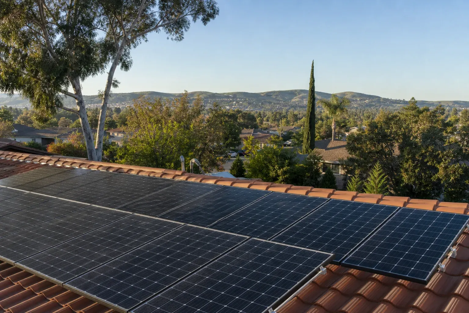 Residential solar panels on a tile roof in a mature tree-lined Orange neighborhood.