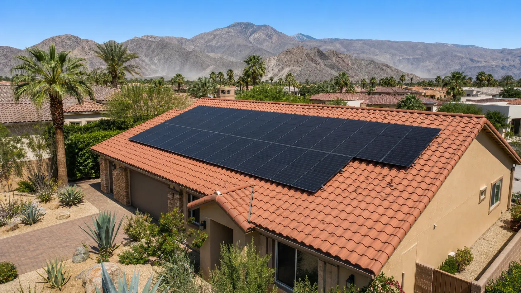 A Coachella Valley Spanish tile roof with rooftop solar panels and desert mountains in the background
