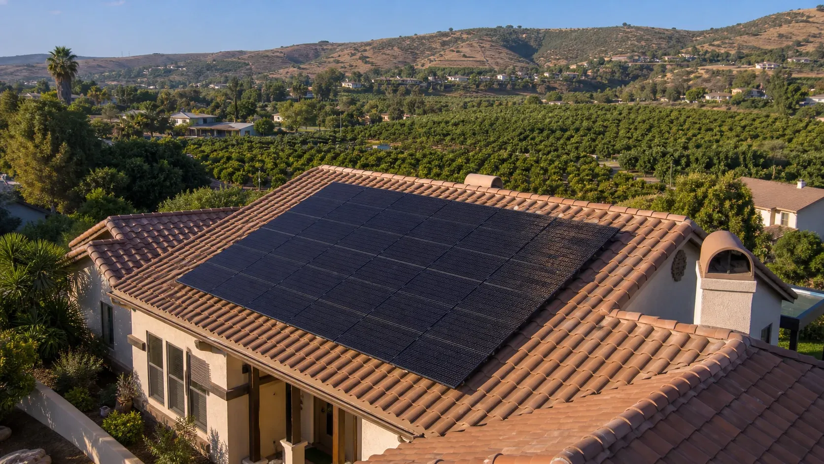 Inland North County home with solar panels on a terracotta tile roof above avocado groves and hills